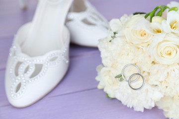 Beautiful wedding bouquet and shoes on wooden background