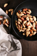 Tasty brasil nuts in pan on wooden background