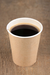 Paper cup of coffee on wooden table