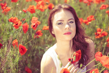 Obraz na płótnie Canvas Beautiful young woman in poppy field