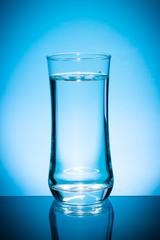 Glass of water isolated on blue background.
