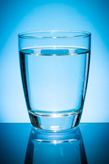 Glass of water isolated on blue background.