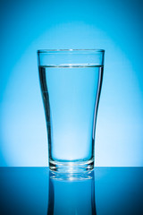 Glass of water isolated on blue background.