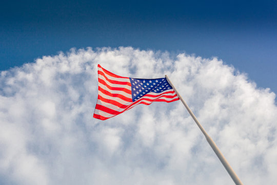American flag waving with cloudy blue sky