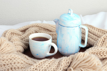 Obraz na płótnie Canvas Cup and teapot with scarf on bed on wall background