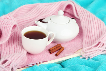 Fototapeta na wymiar Cup and teapot on tray with scarf on fabric background