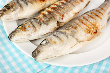 Delicious grilled fish on plate on table close-up