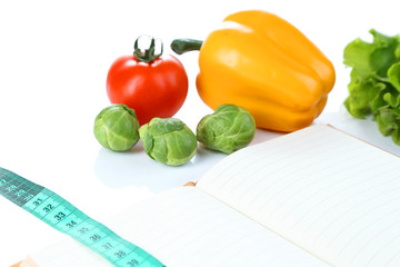 Book with measuring tape and vegetables isolated on white