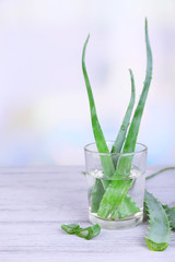 Fresh green aloe leaves in glass on wooden table