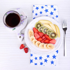 Various sliced fruits on plate on table close-up