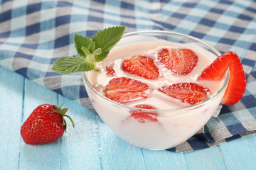 strawberry with yogurt in a glass bowl on a wooden board