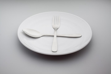 Plates with a silver fork and spoon isolated on gray background