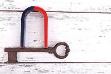 Magnet with old key on wooden background