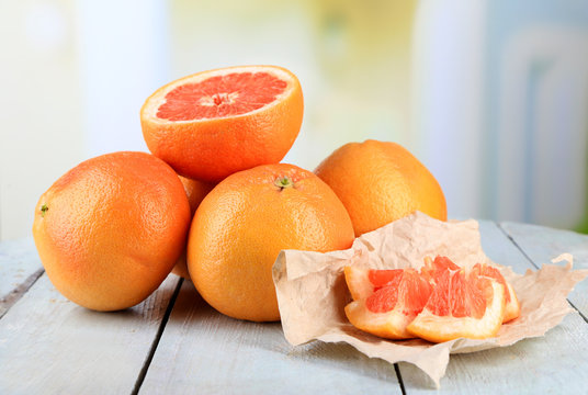 Ripe grapefruits on wooden board, on bright background