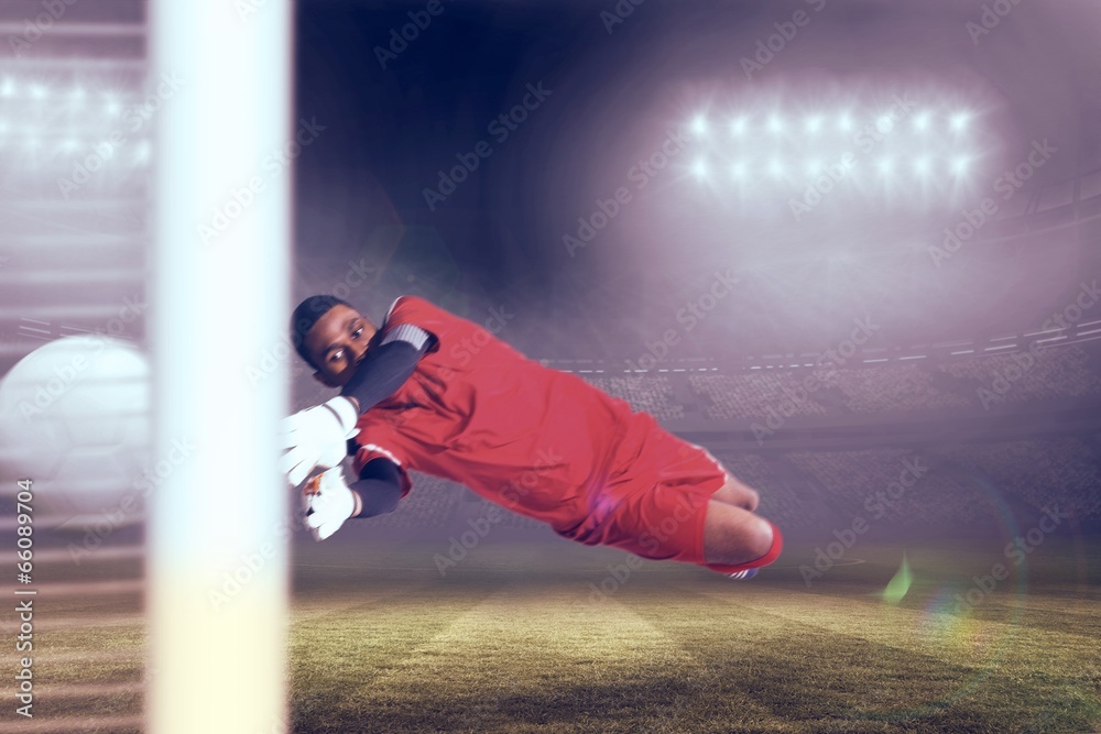 Fototapete composite image of goalkeeper in red making a save