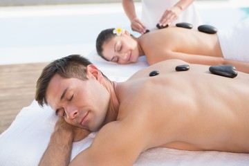 Obraz na płótnie Canvas Attractive couple enjoying hot stone massage poolside