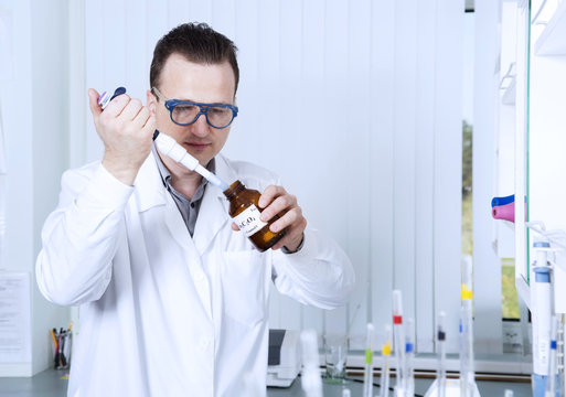 Male scientist with laboratory pipettes