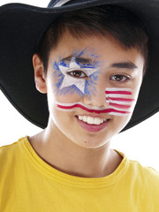 smiling Asian European boy with fancy stars and stripes face paint wears a leather cowboy hat