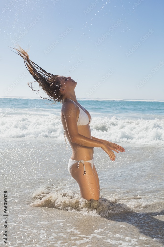 Wall mural beautiful woman in white bikini tossing wet hair