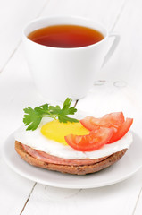 Sandwich with fried egg, tomato slices, salami