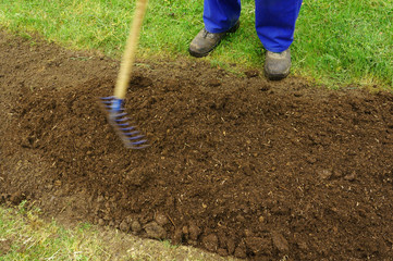 Gartenarbeit, Humus wird mit Rechen verteilt