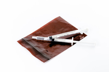 Small syringe lay on brown pill bag on white background,small sy