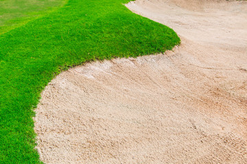 Sand bunker at the golf course and green grass