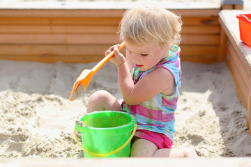 Little toddler girl playing with toys in sandbox