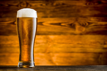 Glass of beer on wooden table and wooden background