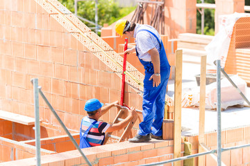 Handwerker kontrollieren Wände auf Baustelle
