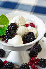 White vanilla ice-cream with berries and mint. Indoors closeup.