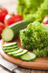 fresh cucumber tomatoes and salad leaves on chopping board