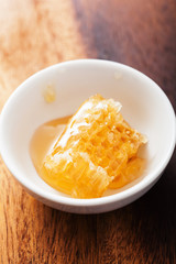 honeycomb in bowl over wooden background