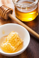 honeycomb dipper and honey in jar on wooden background