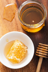 honeycomb dipper and honey in jar on wooden background