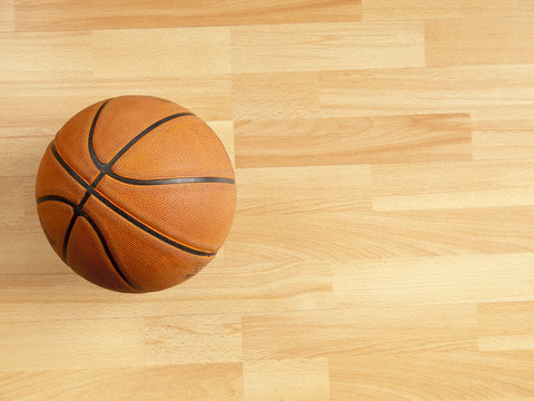An official orange ball on a hardwood basketball court