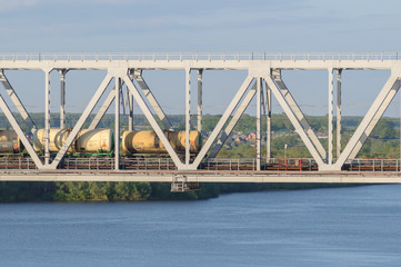 yellow railway tanks on the bridge across the river in summer