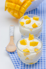 Yoghurt with mango  in a glass jars on white background