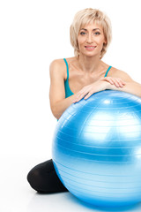 blond lady sitting behind fitness ball.
