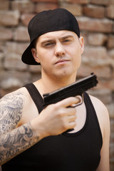 Obraz premium young guy with tattoo holding gun.