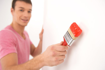 young man painting wall and smiling.