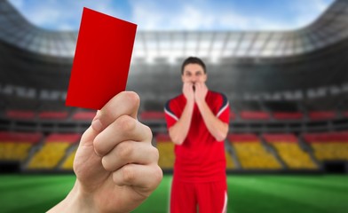 Composite image of hand holding up red card to player