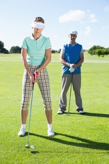 Lady golfer teeing off for the day watched by partner