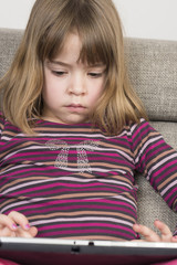 Little girl playing with a digital tablet