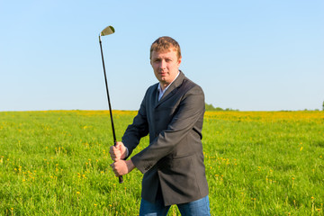 man in a business suit holding a golf club