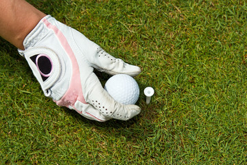 Close-up of a gloved hand of a woman golfer placing golf ball on