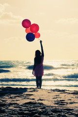 beautiful woman with colorful balloons on seaside
