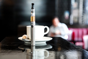 Cup of coffee and e-cigarette on a bar counter