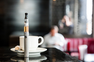 E-cigarette on a bar counter with a cup of coffee