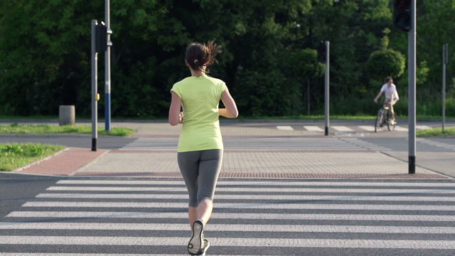 Young woman jogging through zebra crossing
